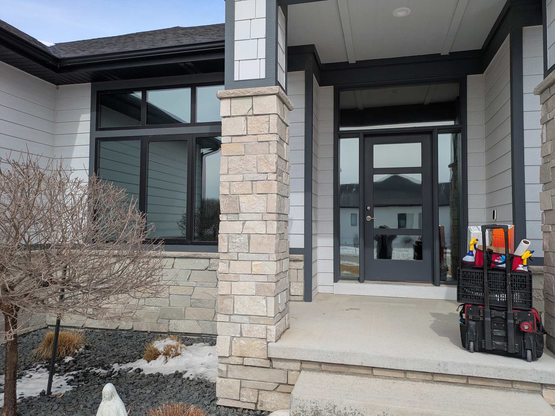 Front entry of a stone and siding home in Dakota Dunes with tall windows
