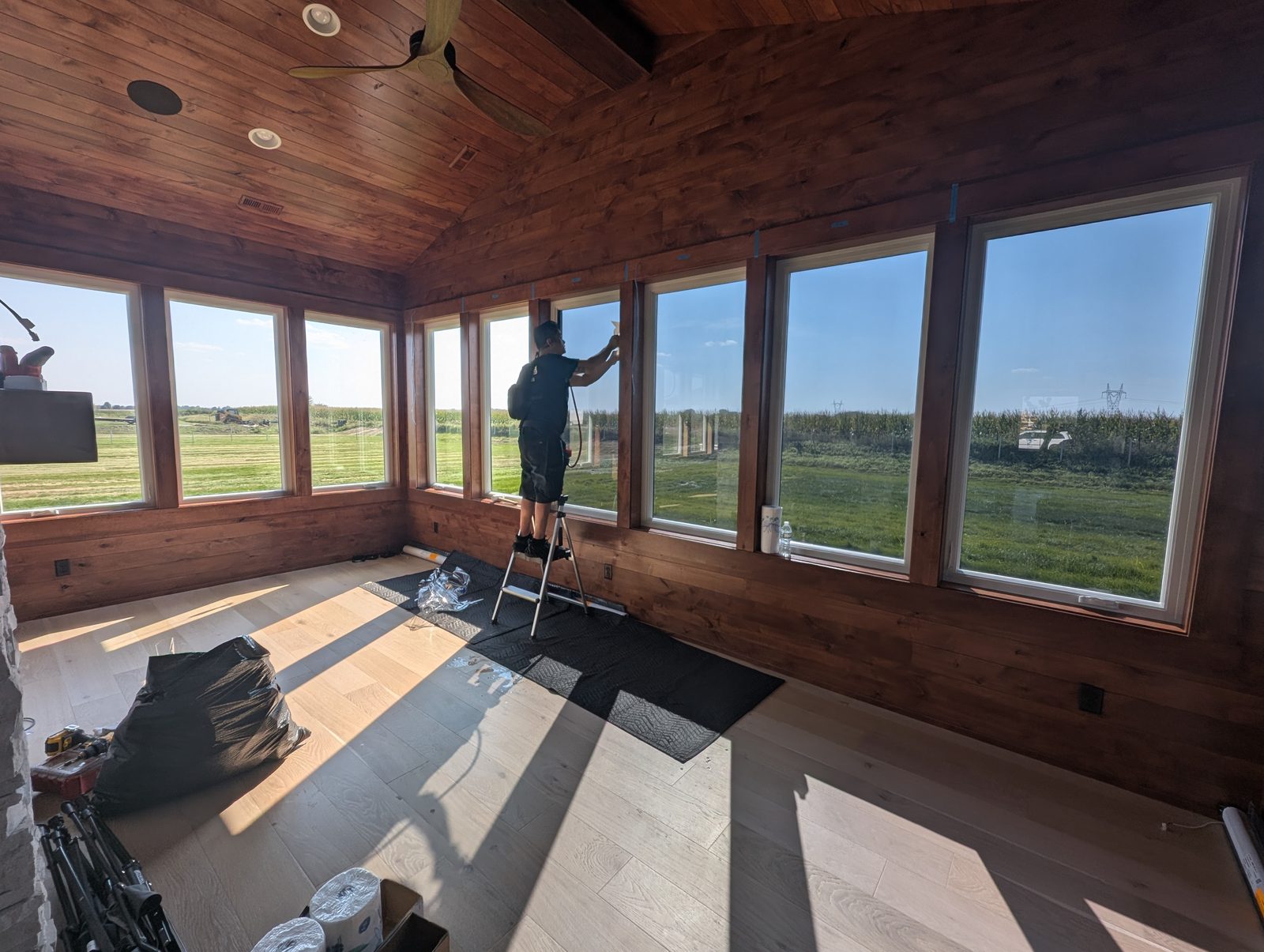 Installer applying window film in a wood-paneled sunroom